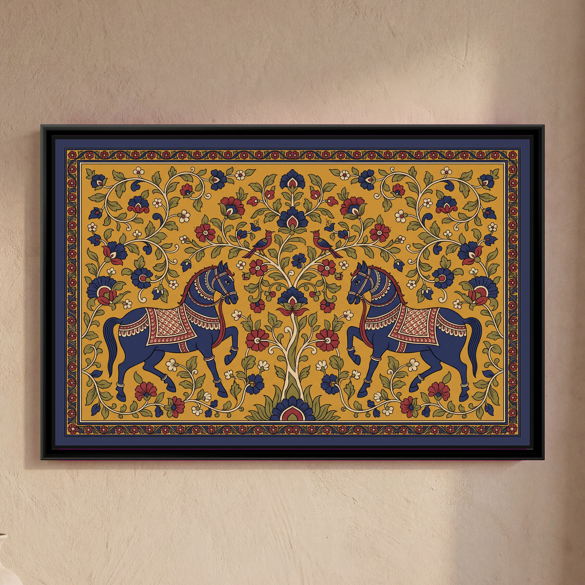Kalamkari Painting – Pair of Horses Facing a Tree of Life - framed canvas print of two indigo horses with patterned red saddle cloths and bridles rearing toward each other on either side of a flowering tree of life, two red birds facing each other in its branches, curling vines with red, indigo and cream flowers and green leaves filling a mustard ground, an indigo and red patterned border, hung on a wall