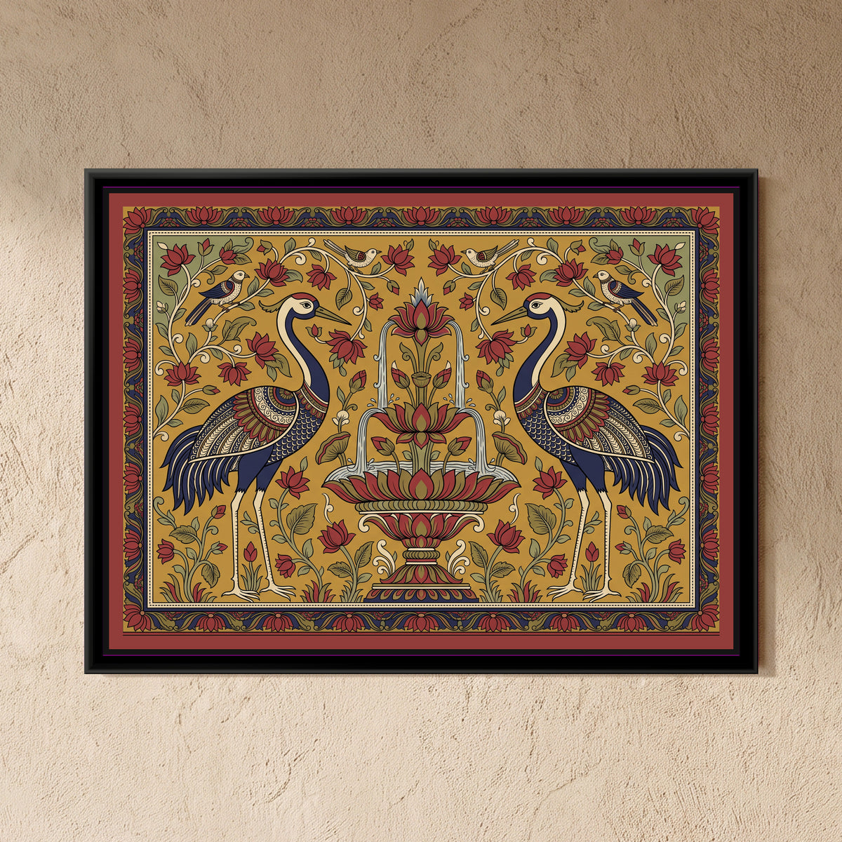 Kalamkari Painting – Cranes Flanking a Lotus Fountain - framed canvas print of two tall cranes with indigo necks and richly patterned red, indigo and cream wings standing face to face on either side of a tiered lotus fountain with water falling in arcs into a lotus basin, small birds perched on curling vines above, red lotus flowers and green leaves on a mustard ground with sage corners, an indigo and red floral border, hung on a wall