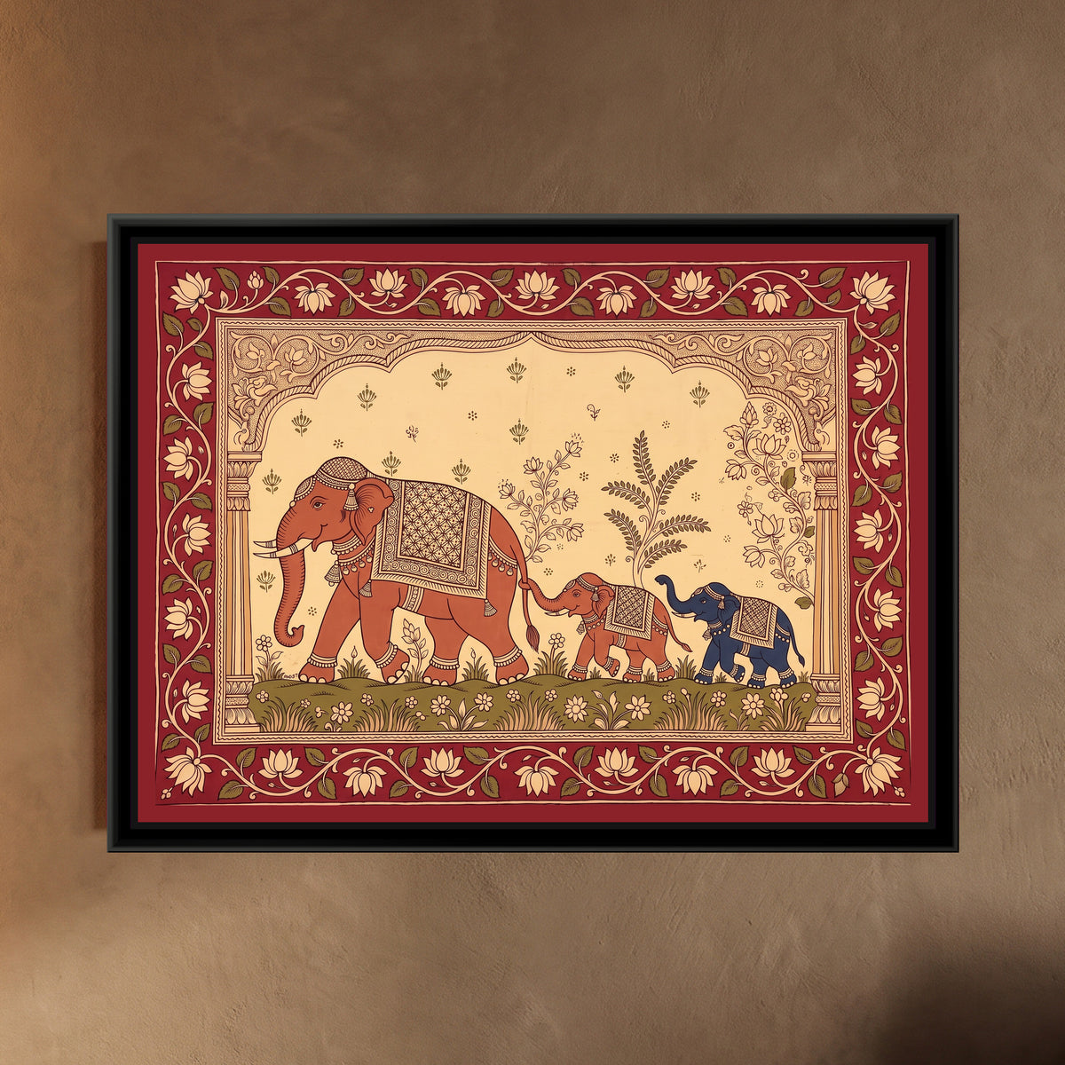 Kalamkari Painting – Elephants and Calves in Procession - framed canvas print of a large terracotta elephant with a patterned saddle cloth, jewelled headpiece, tusks and anklets walking across a green meadow of small flowers, a little terracotta calf holding her tail with its trunk and a little indigo calf trotting behind, leafy plants and flowering sprigs in a cream sky, a carved scalloped arch on two pillars, a deep red border of cream lotuses on a vine, hung on a wall