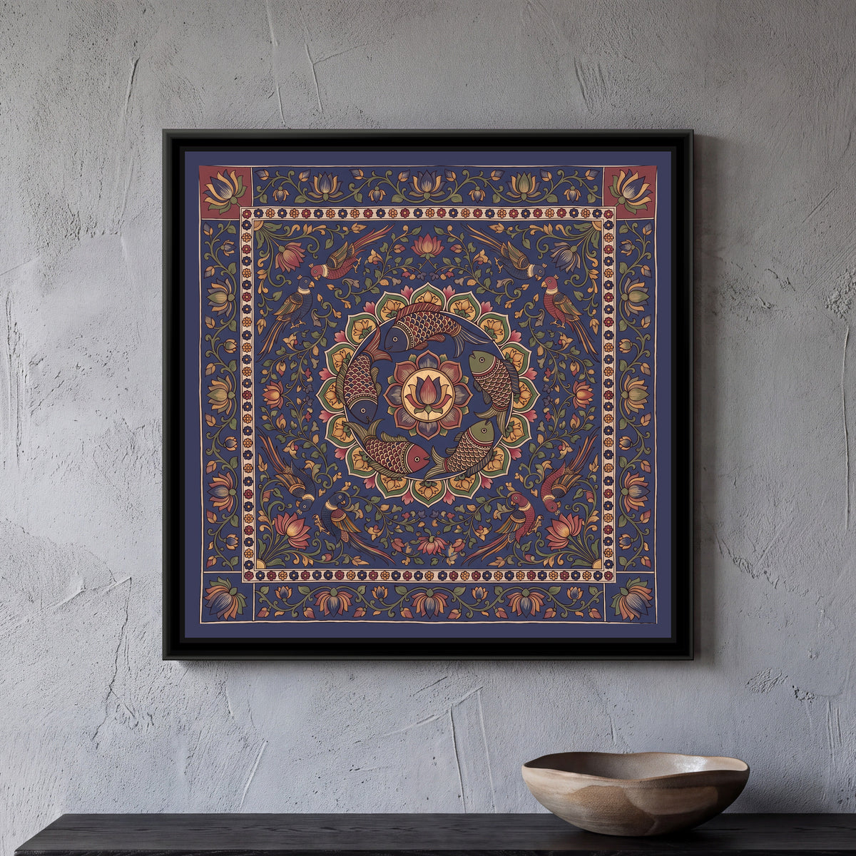 Kalamkari Painting – Fish Mandala – Deep Indigo - framed canvas print of five scaled fish in red, indigo and olive swimming in a ring around a central lotus medallion inside a circle of green and mustard petals, eight parrots in pairs perched among lotus vines at the corners, all on a deep indigo ground, a cream band of tiny flowers, an outer indigo border of lotus vines with two red corner squares at the top, hung on a wall