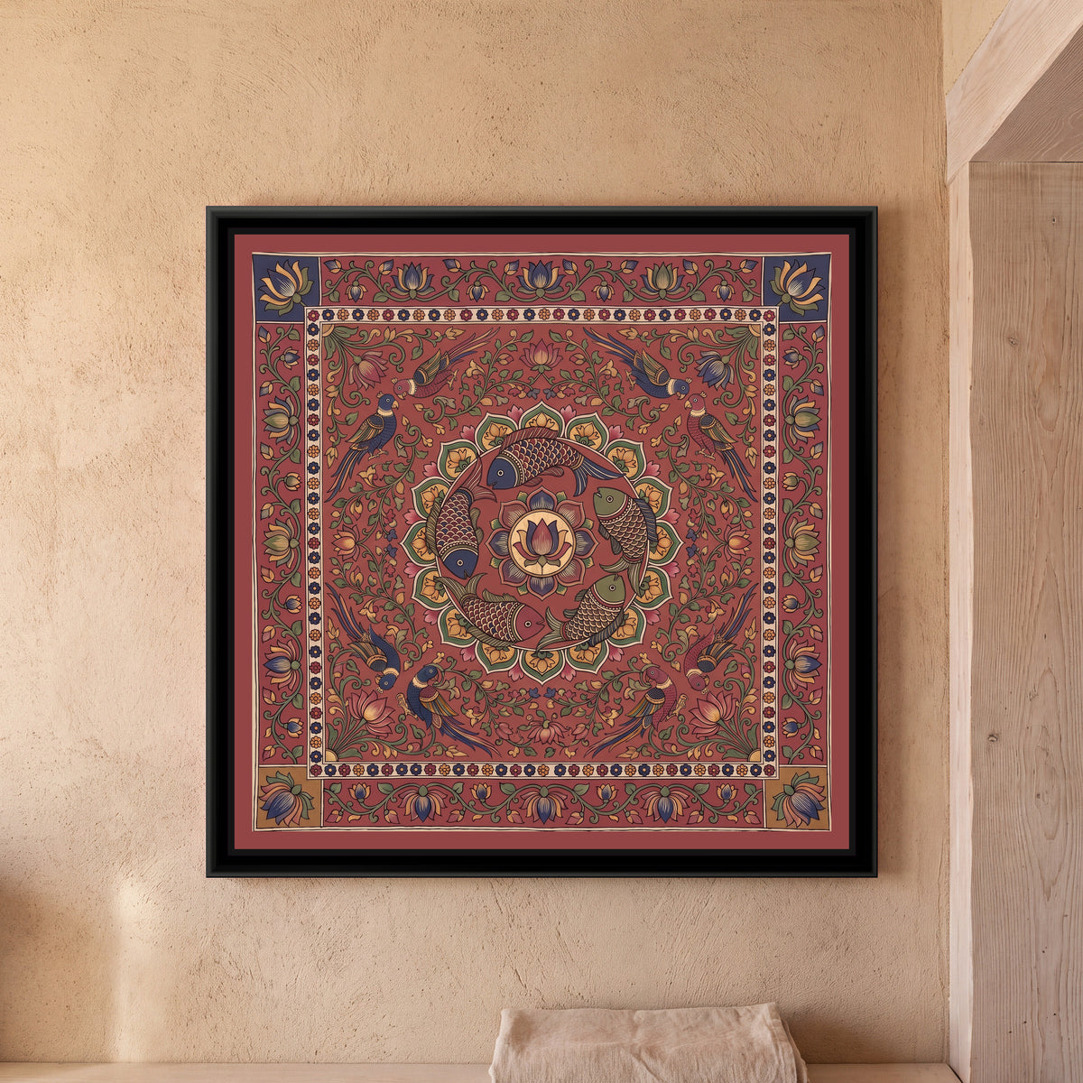 Kalamkari Painting – Fish Mandala – Deep Madder Red - framed canvas print of five scaled fish in red, indigo and olive swimming in a ring around a central lotus medallion inside a circle of green and mustard petals, eight parrots in pairs among lotus vines, all on a deep madder red ground, a cream band of tiny flowers, an outer madder red border of lotus vines with indigo and mustard corner squares, hung on a wall
