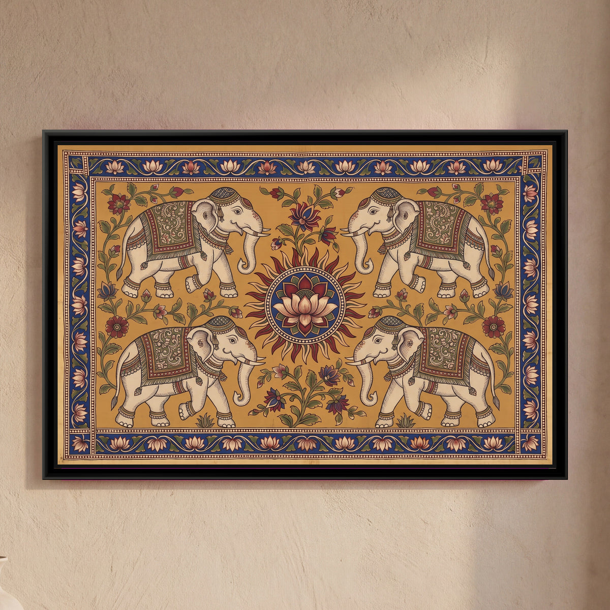 Kalamkari Painting – Four Elephants around a Sun Medallion - framed canvas print of four cream elephants wearing patterned green and red saddle cloths, caps and anklets, two above and two below, walking towards a central red-rayed sun with a cream lotus on an indigo disc, flowering creepers on a warm ochre ground, inside a deep indigo border of pink lotuses on a vine, hung on a wall