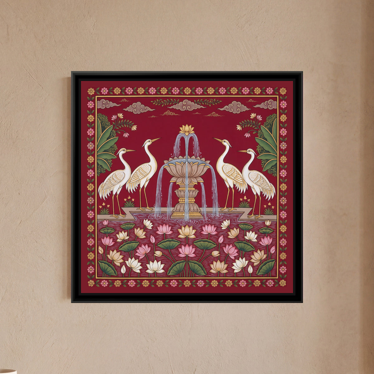 Pichwai Painting – Cranes around a Lotus Fountain - framed canvas print of four white cranes with gold-edged wings, two on each side, standing on a stone ledge facing a tiered lotus-shaped fountain spraying silver water, a pond below crowded with pink, cream and gold lotuses and green lotus pads, banana leaves and flowering sprays in the upper corners, soft clouds along the top, a deep red ground, a border of small pink and gold flowers on a vine, hung on a wall