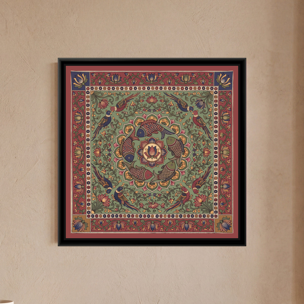 Kalamkari Painting – Fish Mandala – Sage Green - framed canvas print of five scaled fish in red, indigo and olive swimming in a ring around a central lotus medallion inside a circle of green and mustard petals, eight parrots in pairs among lotus vines, all on a sage green ground, a cream band of tiny flowers, an outer madder red border of lotus vines with indigo and mustard corner squares, a flat red outer edge, hung on a wall