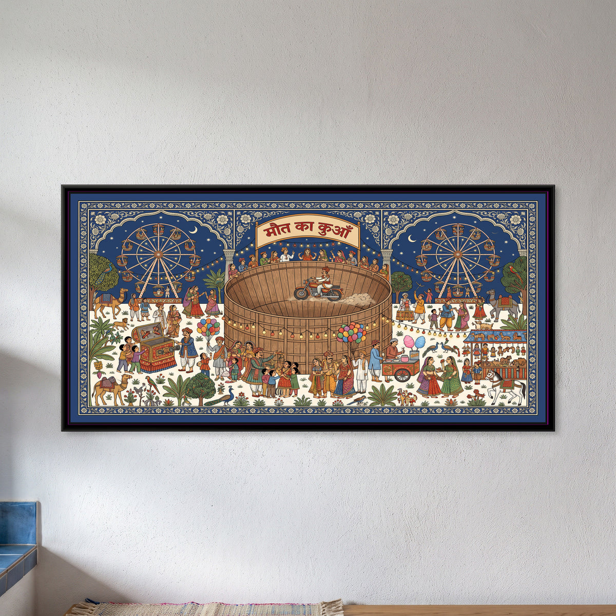 Phad Painting – The Great Indian Mela - framed canvas print of a wide Phad-style night mela, a motorcyclist riding the wall of a round wooden Maut Ka Kuan under a Devanagari banner, two giant wheels on a starry cobalt sky, strings of bulbs, a bioscope box with children, balloon and candy floss sellers, a toy stall, camels, peacocks and crowds of families, inside a blue floral border, hung on a wall
